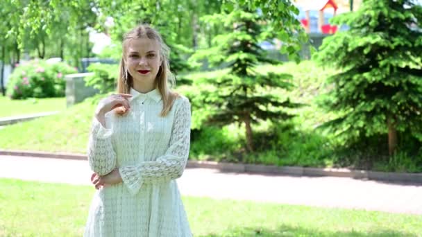 Video of a pretty blonde in a park with a smile. Girl with great makeup posing in sunny weather. — Stock Video