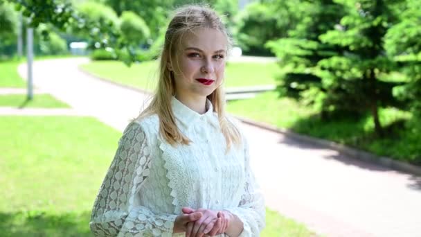 Portrait of a caucasian smiling model with excellent make-up in the park in sunny weather. Video of a pretty blond girl — Stock Video
