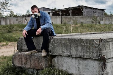 Çevre felaketi kavramı. Harabelerin üzerinde gaz maskeli bir adamın fotoğrafı var. Hoşnutsuz görünüyor..