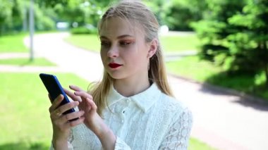 Parkta konuşan sarışın kızın video portresi.