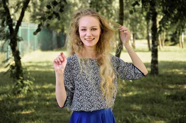 Portrait d'une fille blonde caucasienne souriant dans un parc. Photo d'une jolie jeune femme aux beaux cheveux par temps ensoleillé. Plein air concept de beauté — Photo
