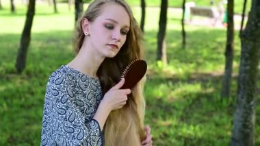 Kafkasyalı sarışın kadın parkta saçını tarıyor..