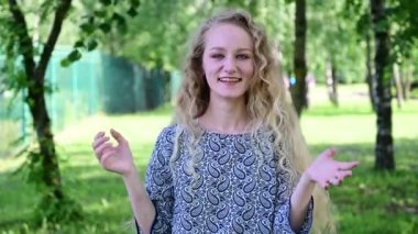 Kafkasyalı sarışın bir kızın, güzel saçlı bir yaz parkında gülüşünün videosu..