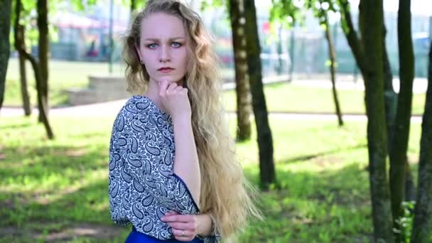 Video serious caucasian blonde girl with beautiful hair in a summer park. — Stock Video