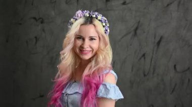 Gri arka planda gülümseyen aktif, neşeli bir kadın..