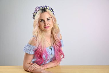 Kafasında çelenk olan güzel bir kadının portresi. Stüdyoda beyaz arka planda gülümseyen sarı saçlı manken.