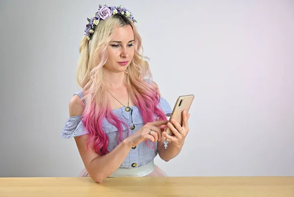 携帯電話を手にしたきれいな女性の肖像画 ブロンド色の髪モデルともに笑顔花輪ポーズでスタジオ上の白の背景 — ストック写真