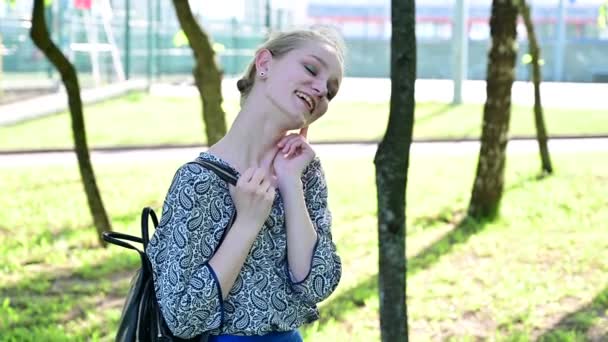 En ung charmig flicka i en sommarpark skrattar glatt. — Stockvideo