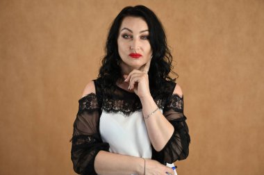 Bej arka planda konuşan güzel bir mankenin yakın plan portresi. Esmer bir kadın stüdyoda duruyor.