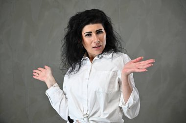 Duygusal olarak ifade edilebilen, beyaz takım elbiseli, gri arka planda, beyaz elbiseli, beyaz saçlı, oldukça beyaz bir kadının portresi.