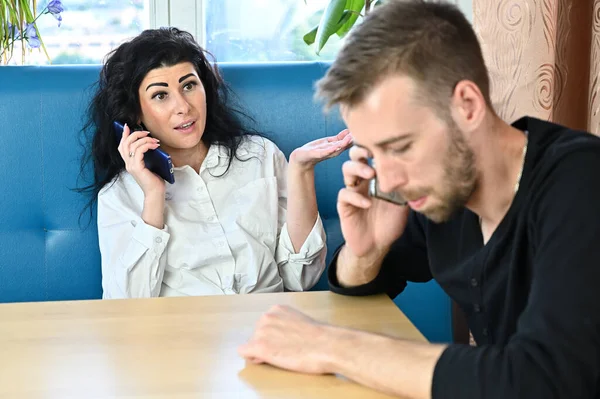 Evdeki bir odada oturan genç bir adam ve kadının elinde telefonla mutsuz bir aile sohbeti fotoğrafı. — Stok fotoğraf