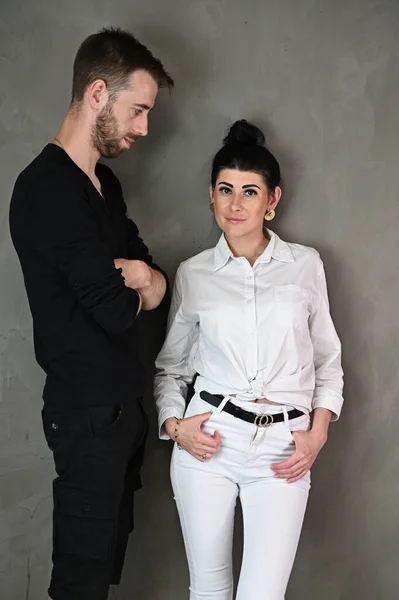 Stylish vertical studio portrait of a caucasian brunette woman and man in a love relationship on a gray background — Stock Photo, Image