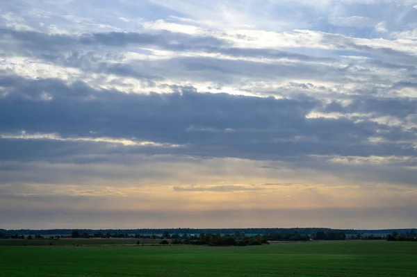 Landschapsfoto van een blauwe lucht tegen een groen veld in de ondergaande zon in de herfst — Stockfoto