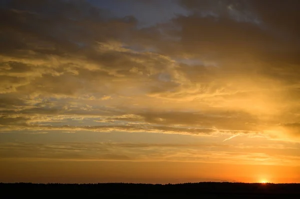 Paisagem foto do céu entardecer no outono contra o fundo de um campo verde no sol laranja — Fotografia de Stock