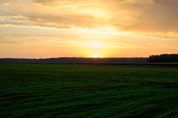 Φωτογραφία του βραδινού ουρανού ηλιοβασίλεμα το φθινόπωρο με φόντο ένα πράσινο πεδίο — Φωτογραφία Αρχείου