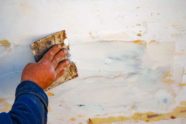 A Man repairing or renovation wooden fishing boat surface.