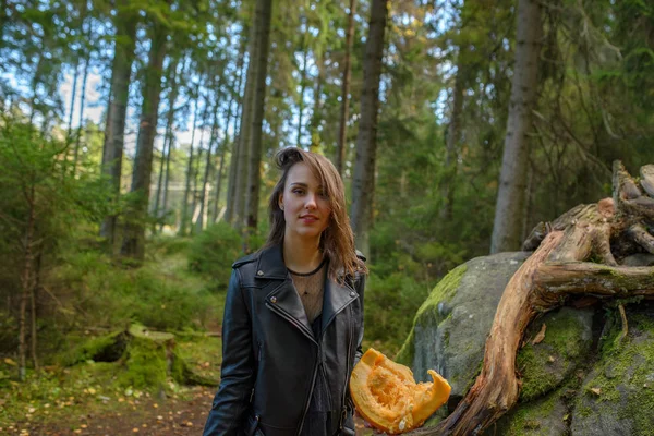 Νεαρή όμορφη γυναίκα στο δερμάτινο μπουφάν με κολοκύθα σε ένα δάσος — Φωτογραφία Αρχείου