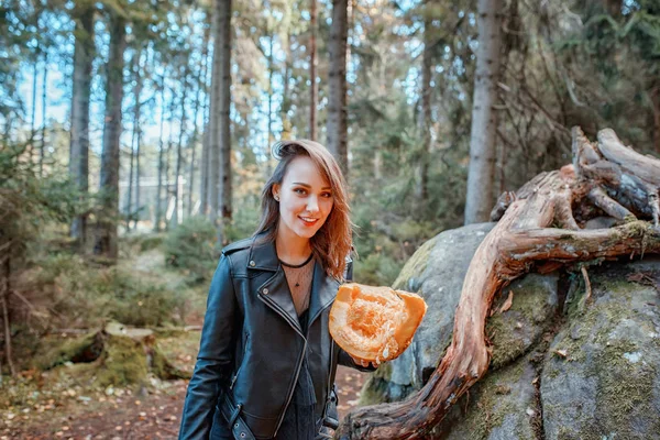 Jovem mulher bonita em jaqueta de couro com abóbora em uma floresta — Fotografia de Stock