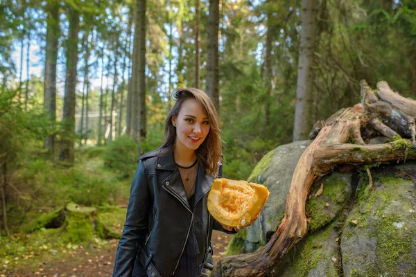 Молодая красивая женщина в кожаной куртке с тыквой в лесу — стоковое фото