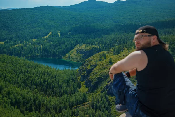 Dağların zirvesinde sırt çantalı ve güneşli bir günde güzel dağlarda duran sportif adam..