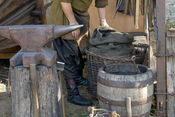 blacksmith in a medieval forge preparing to workblacksmith medieval blacksmith with an anvil, a barrel and a basket with coal