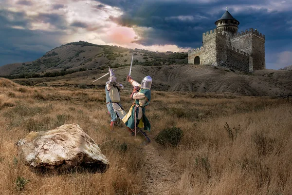 日没の空を背景に城の近くで2人の騎士の間で戦う — ストック写真