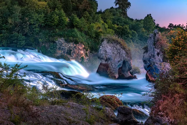 長い露出で撮影夕日の最後の光線によって照らされたラインの滝 ロイヤリティフリーのストック画像