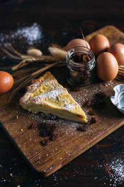 Ricotta peyniri ve kuru üzüm, yumurta, kavanoz ve ahşap arka plan üzerinde pudra şekeri ile geleneksel İtalyan kek, seçici odak