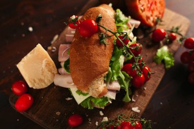 Ahşap arka planda peynir, jambon, salata, domates ve parmesan ile geleneksel İtalyan sandviç