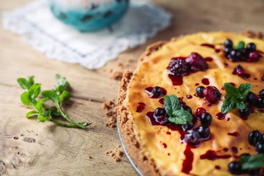 Kırmızı meyve, nane ve ahşap arka plan üzerinde pudra şekeri ile güzel geleneksel İtalyan cheesecake