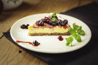 Kırmızı meyve, nane ve ahşap arka plan üzerinde pudra şekeri ile güzel geleneksel İtalyan cheesecake