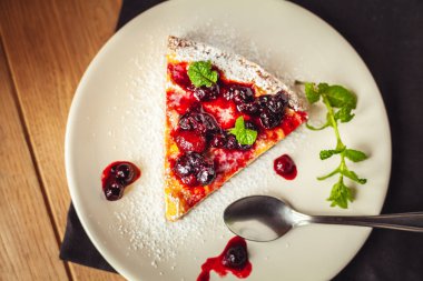 Kırmızı meyve, nane ve ahşap arka plan üzerinde pudra şekeri ile güzel geleneksel İtalyan cheesecake