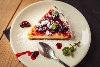 Kırmızı meyve, nane ve ahşap arka plan üzerinde pudra şekeri ile güzel geleneksel İtalyan cheesecake