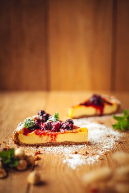 Kırmızı meyve, nane ve ahşap arka plan üzerinde pudra şekeri ile güzel geleneksel İtalyan cheesecake