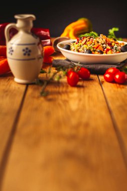 Havuç, biber, domates, maydanoz ve yağ: etrafında bazı malzemeler ile ahşap arka plan üzerinde bir büyülenmiş çanak bir görünüm