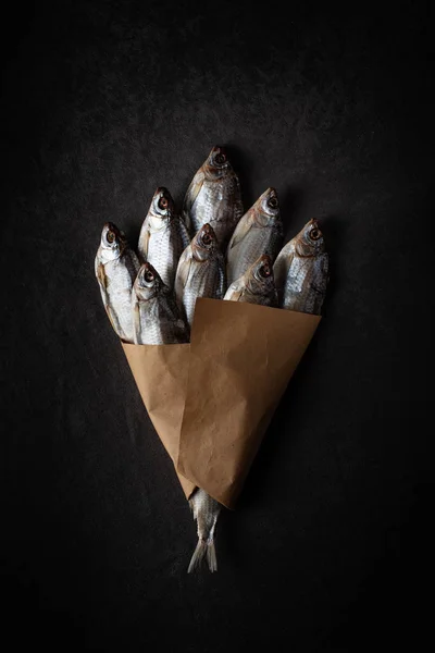 Un ramo de pescado seco sobre un fondo negro con papel artesanal —  Fotos de Stock