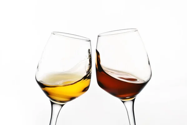 Склянка з бризками червоного та білого вина на білому тлі крупним планом. Вид збоку . — стокове фото