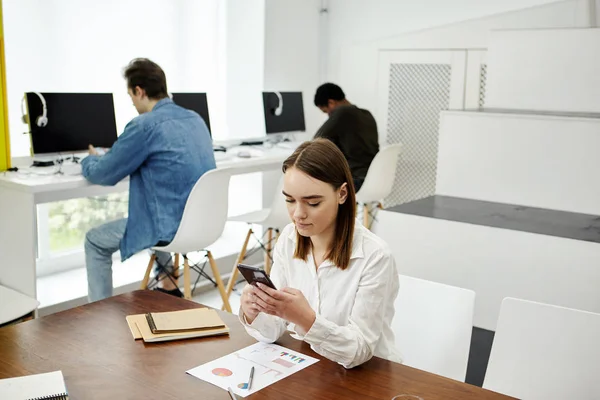 Two faceless men and young woman using smartphones in modern library