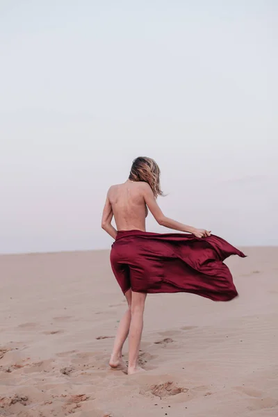 Dziewczyna w czerwonej tkaninie w promieniach słońca na pustyni — Zdjęcie stockowe