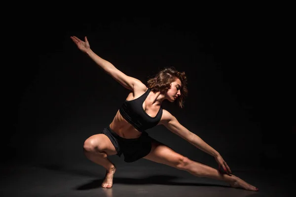 Chica joven haciendo yoga sobre un fondo negro —  Fotos de Stock