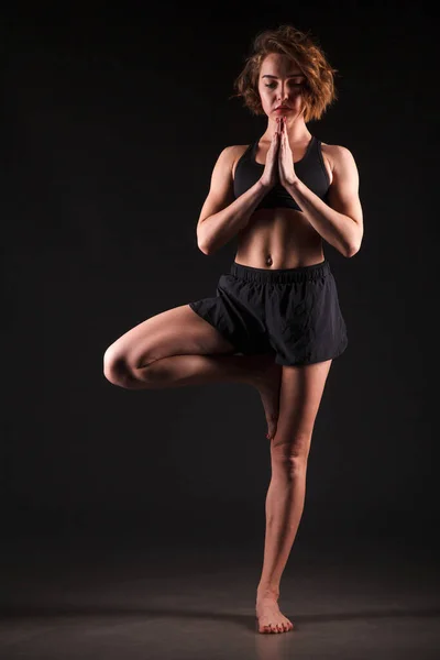 Young girl doing yoga on a black background — Stock Photo, Image