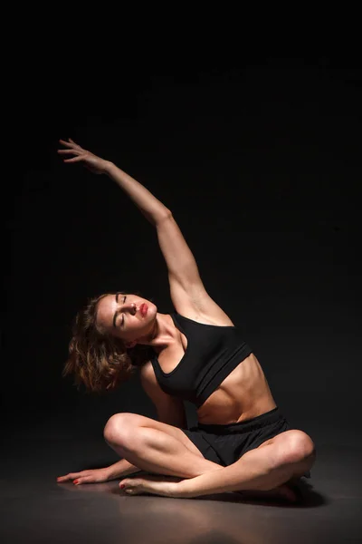 Jeune fille faisant du yoga sur un fond noir — Photo