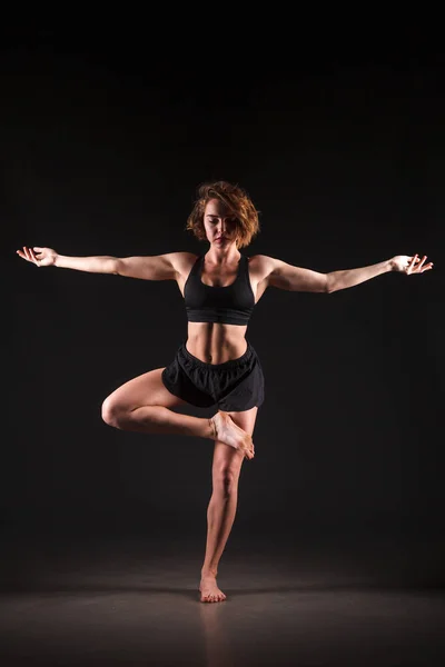 Menina fazendo ioga em um fundo preto — Fotografia de Stock