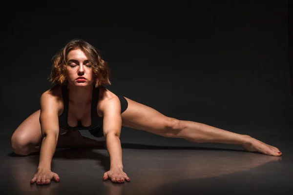 Jeune fille faisant du yoga sur un fond noir — Photo