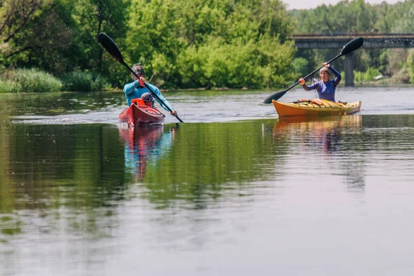 Jóvenes balsas familiares en un río tranquilo y hermoso en dos kayaks —  Fotos de Stock
