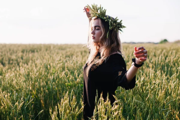 Menina jovem, esbelta em uma grinalda de espigas de trigo ao pôr do sol em um campo — Fotografia de Stock