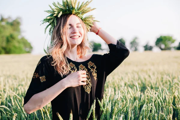 Ung, smal flicka i en krans av veteöron vid solnedgången på ett fält — Stockfoto