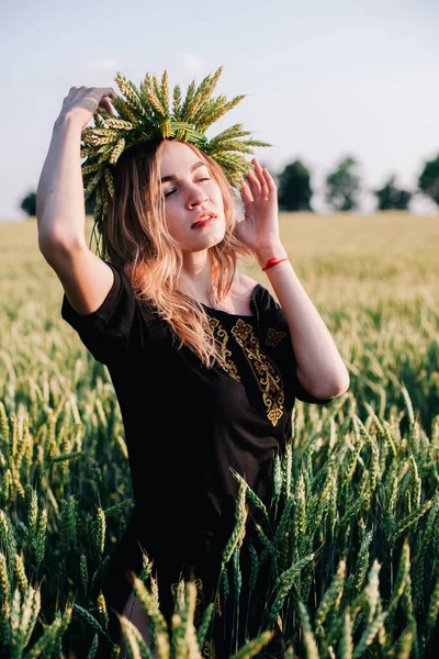 Ung, smal flicka i en krans av veteöron vid solnedgången på ett fält — Stockfoto