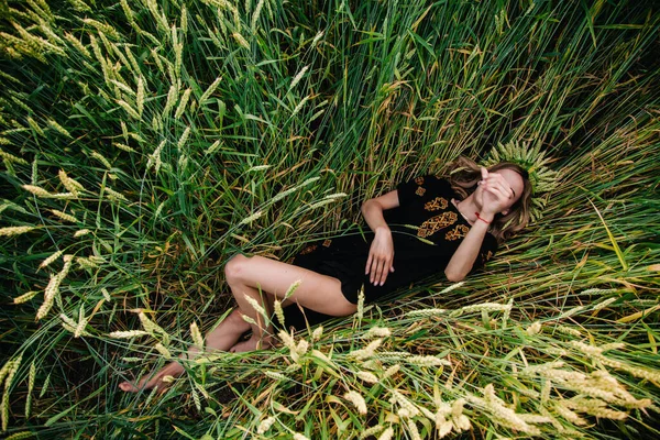 Μια νέα, λεπτή κοπέλα με κέντημα βρίσκεται σε στάχυα σιταριού σε ένα χωράφι. — Φωτογραφία Αρχείου