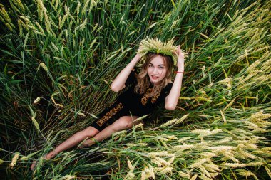 Nakış işlemiş genç, narin bir kız tarladaki buğday başaklarında yatıyor.